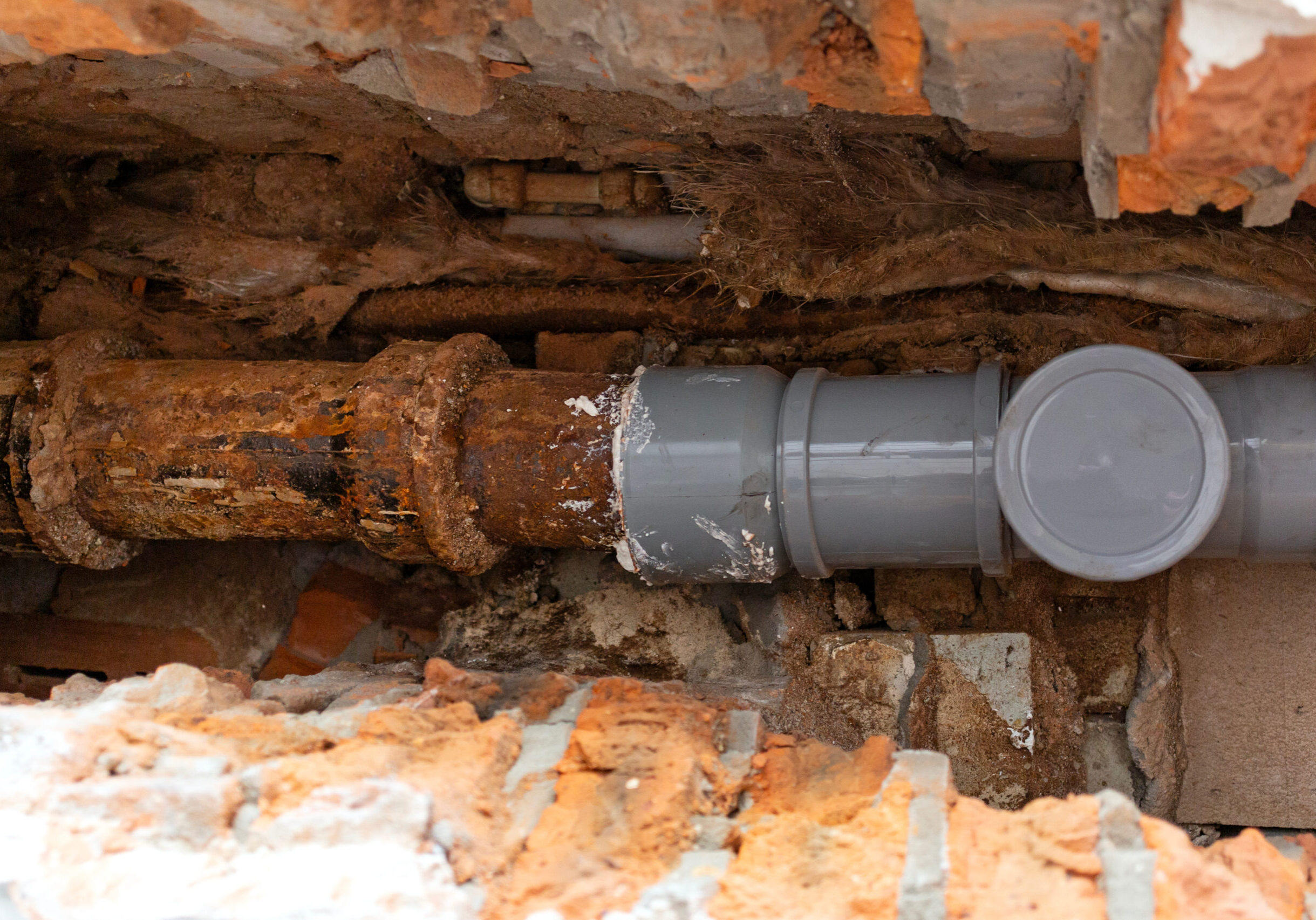 Sewer pipe repair. Partial replacement of the old cast iron pipe with a new plastic one.